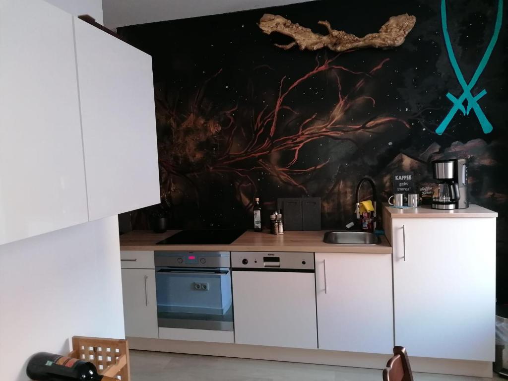 een keuken met witte kasten en een schilderij aan de muur bij City Apartment #1 bei der Porzellan Manufaktur in Meißen
