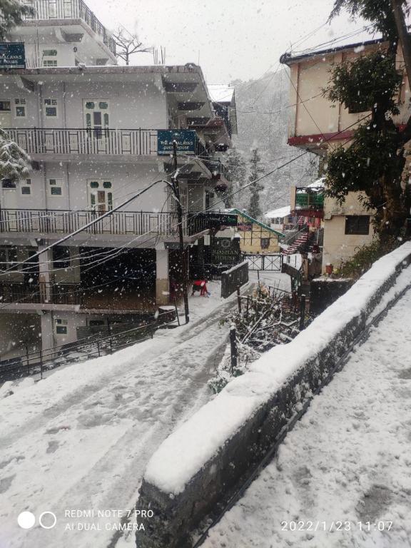 una calle cubierta de nieve en una ciudad con edificios en THE HIMALAYAS GUEST HOUSE, en Dharamshala