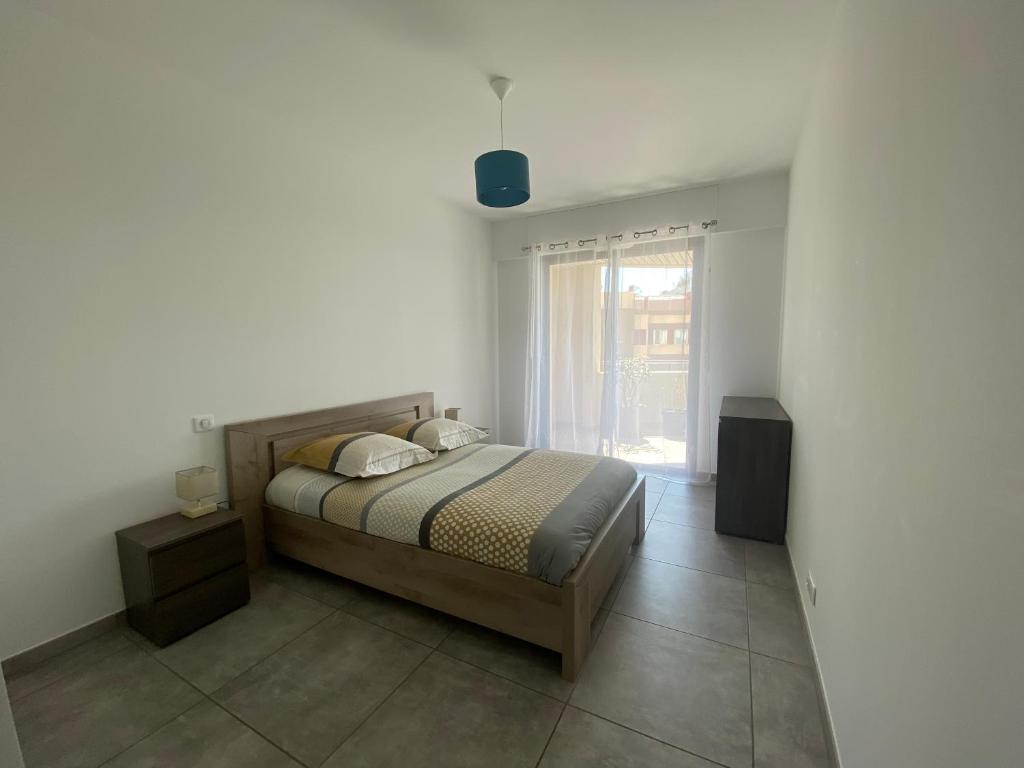 um quarto com uma cama e uma grande janela em Appartement T2 de standing avec parking à 250 mètres de la plage, route des Sanguinaires, Ajaccio em Ajaccio