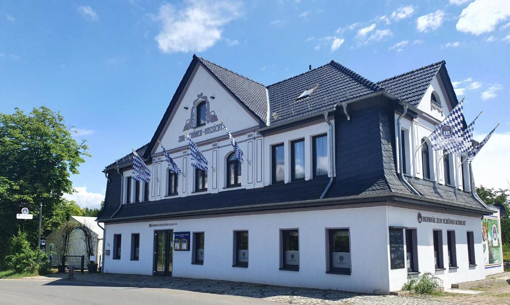 ein weißes Gebäude mit schwarzem Dach in der Unterkunft Hofbräu Zur Schönen Aussicht in Nordhausen