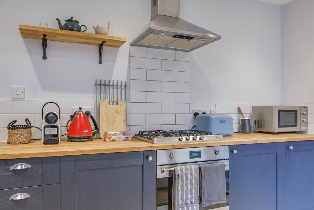 a kitchen with blue cabinets and a stove top oven at The Sands Sheringham in Sheringham