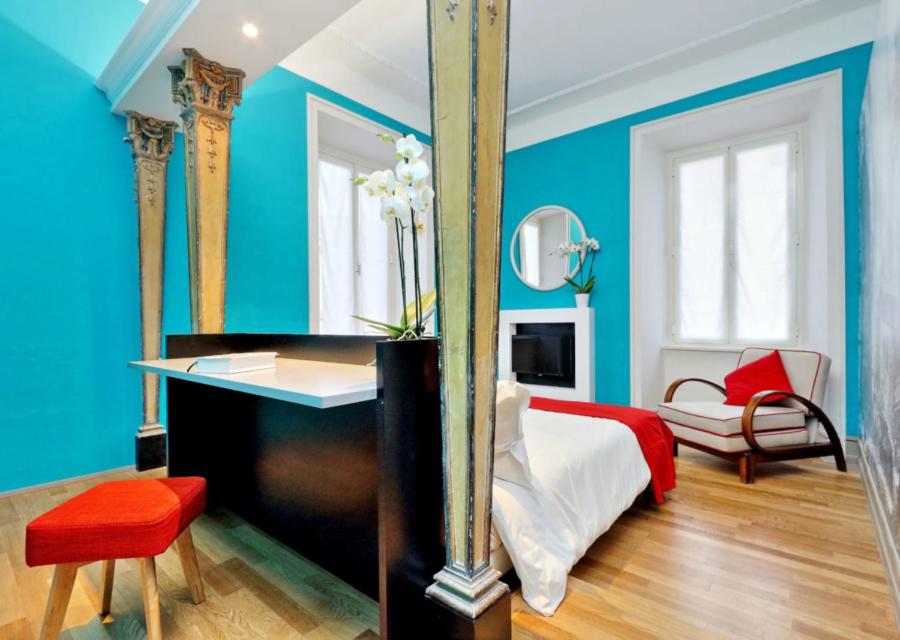 a bedroom with blue walls and a bed with a desk at Piranesi Charmsuite in Rome