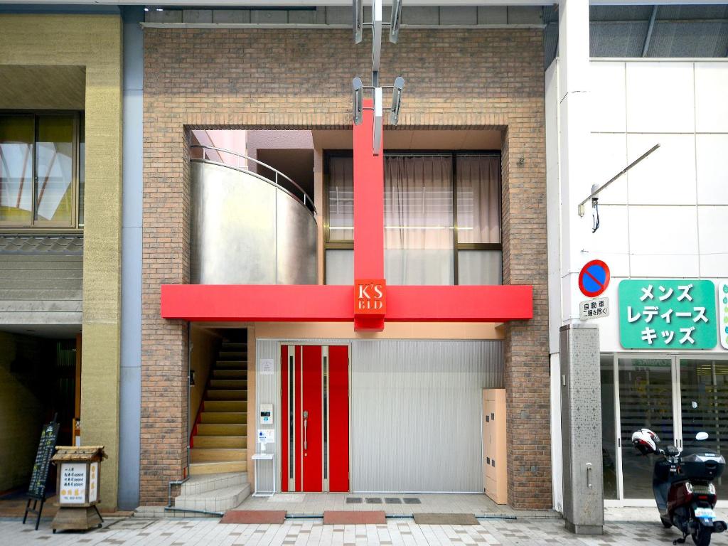 ein Backsteingebäude mit einer roten Tür und einem Schild in der Unterkunft K's Hotel in Takamatsu