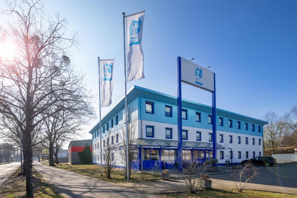 um edifício com bandeiras à sua frente em T3 Budget Berlin Hennigsdorf em Hennigsdorf