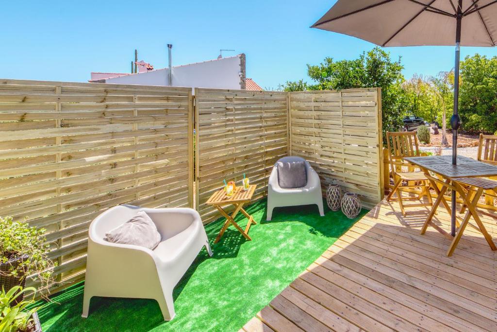 a backyard with two chairs and a table and an umbrella at Casa Amarelo-Tiny House with fantastic view-pool and close to the beaches in Silves