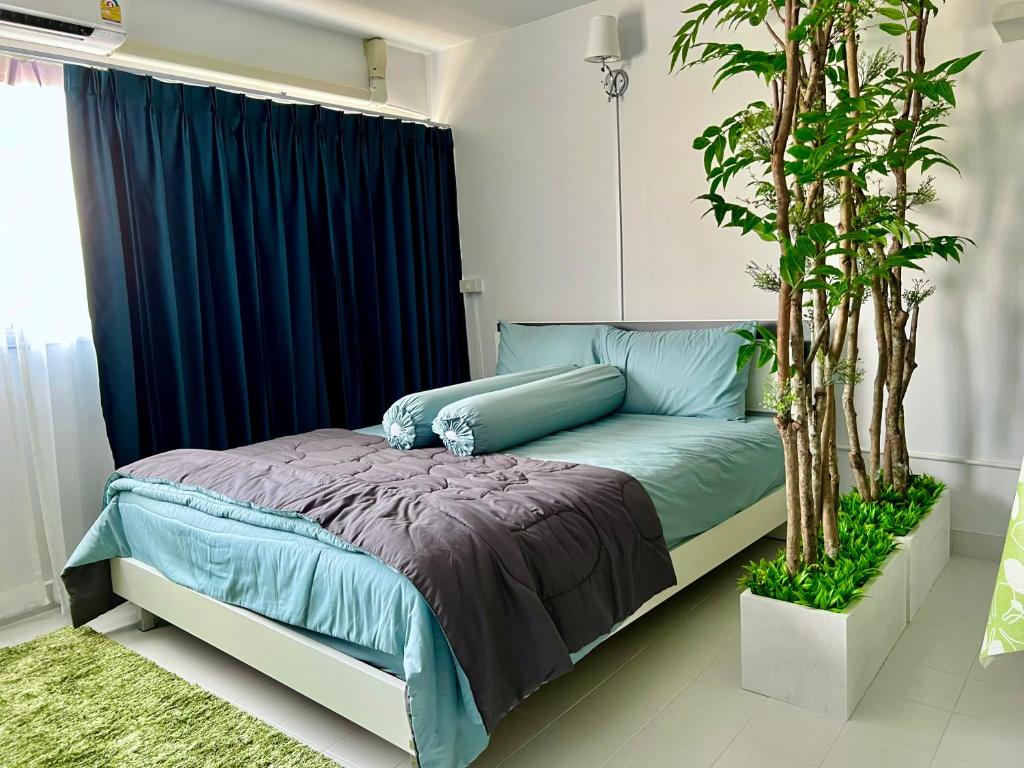 una camera da letto con un letto con lenzuola blu e un albero di C9 Popula Condo by Prathomlerk a Nonthaburi