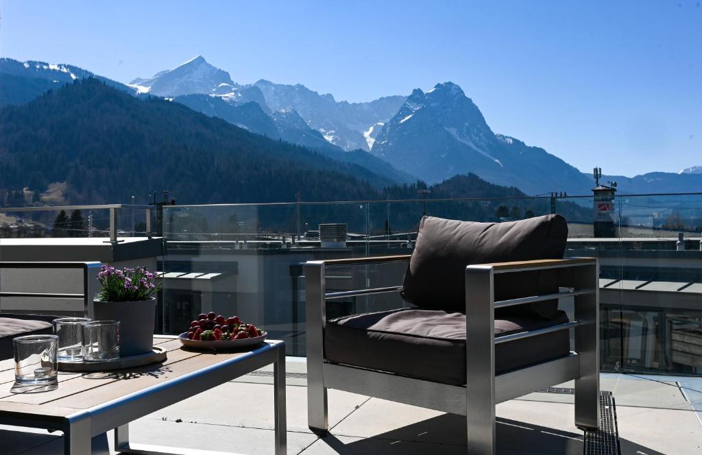 una silla en el balcón con vistas a las montañas en Apartment BergArt en Garmisch-Partenkirchen