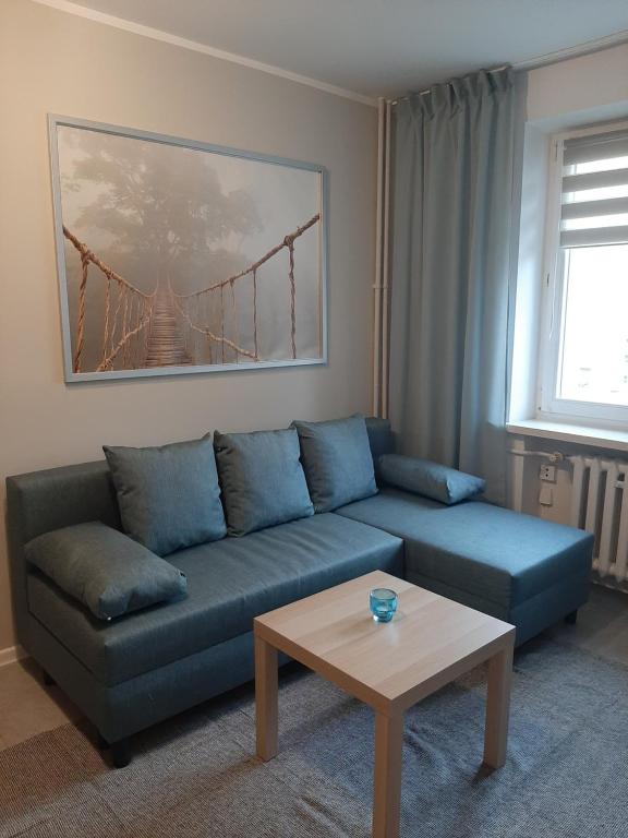 a living room with a blue couch and a table at Apartament Zamkowy in Malbork