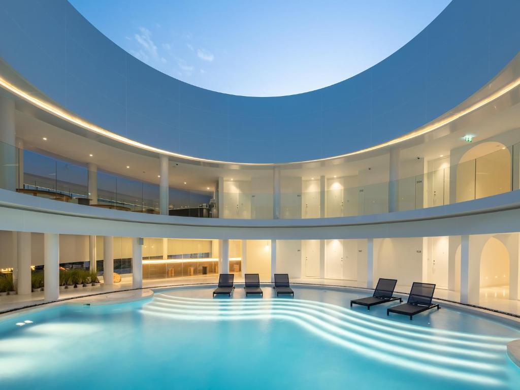 a large swimming pool with chairs in a building at G Nimman Chiang Mai in Chiang Mai