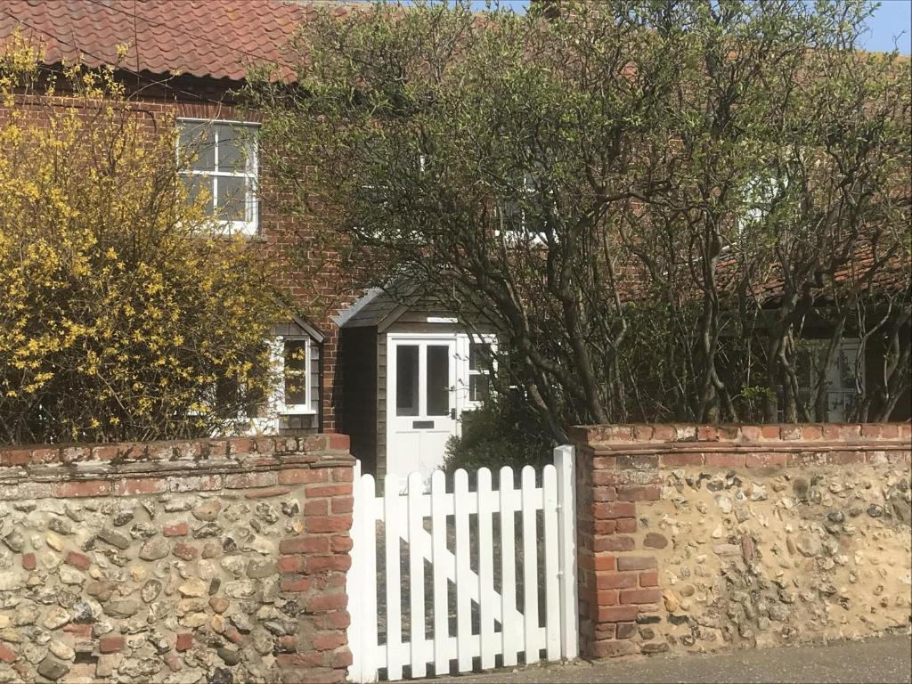 ein weißer Zaun vor einem Haus mit einem weißen Tor in der Unterkunft Lovely 3-Bed Cottage in Brancaster Staithe in Brancaster