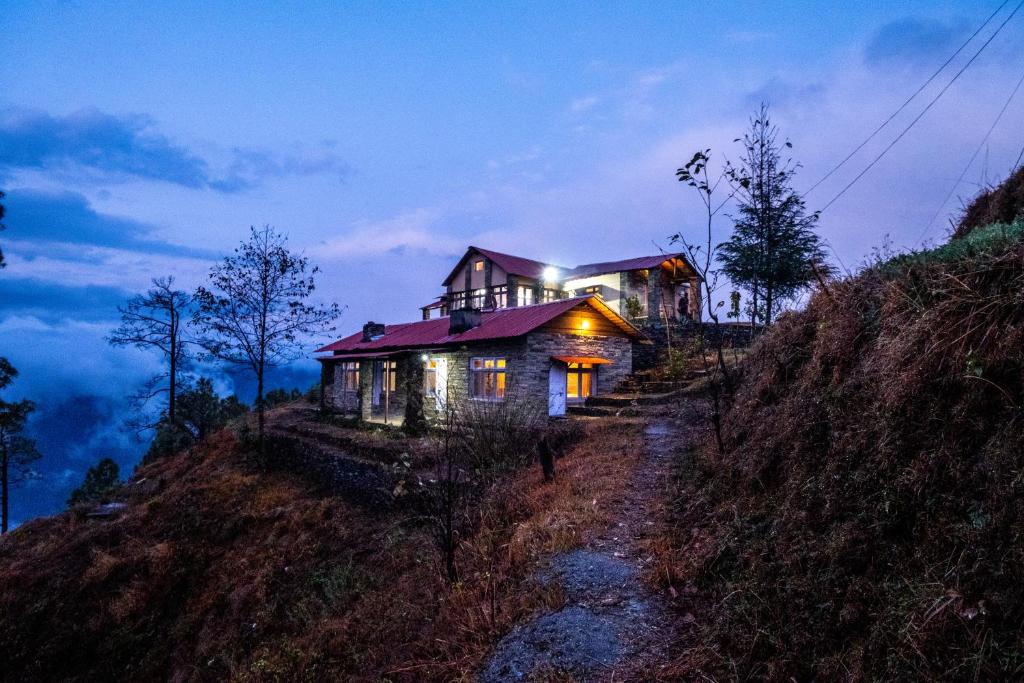 a house on top of a hill at night at Himalayan Paradise, Boutique room w Binsar view by Roamhome in Almora
