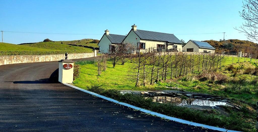 a house on a hill next to a road with a tunnel at Ros na gCloch in Westport