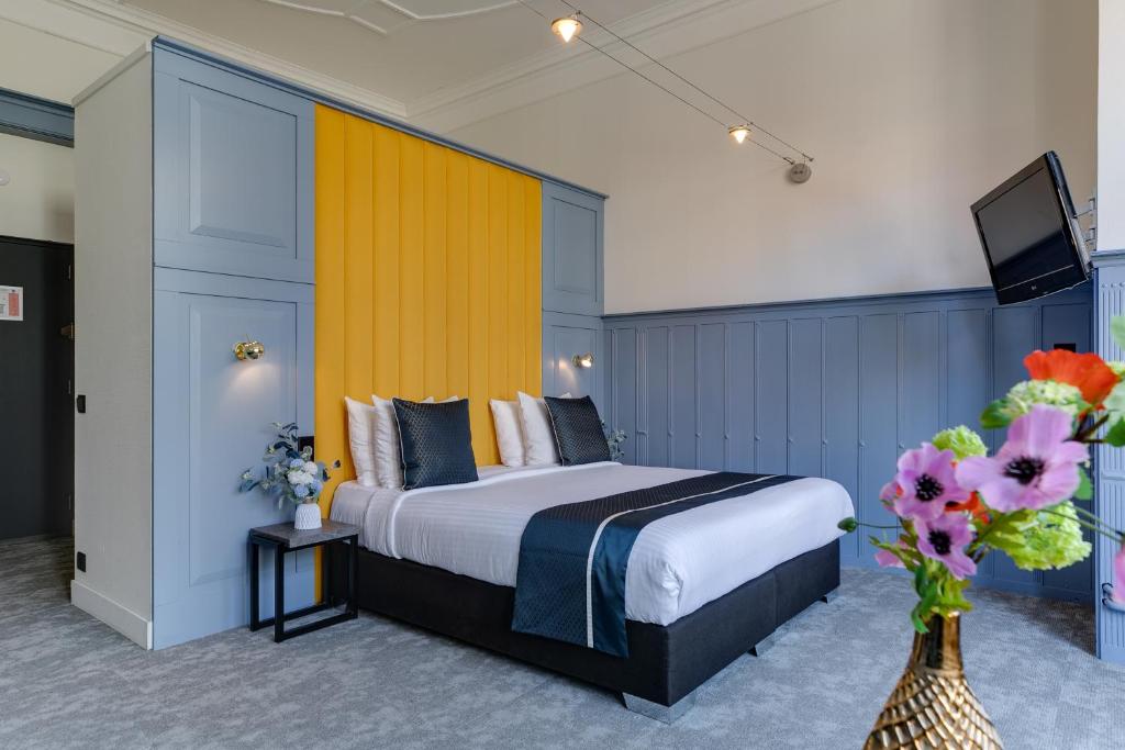 Hotel Royal Bridges في ديلفت: غرفة في الفندق بها سرير و مزهرية من الزهور