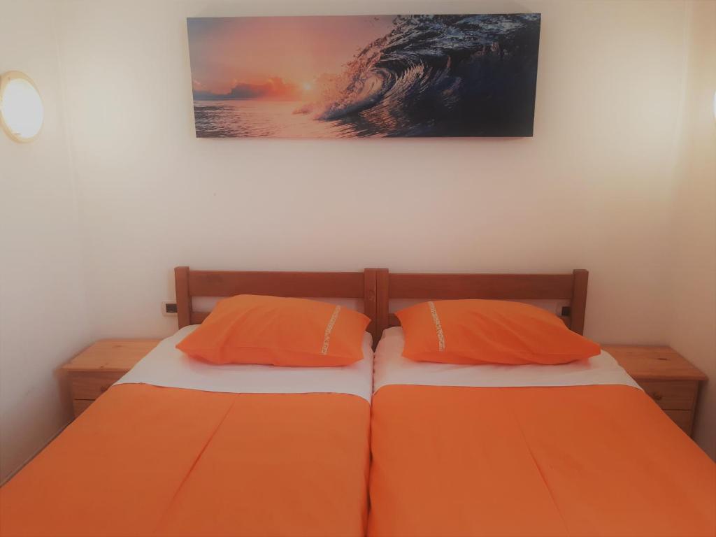 two beds with orange pillows in a bedroom at Apartments Barbara Gregovica in Pula