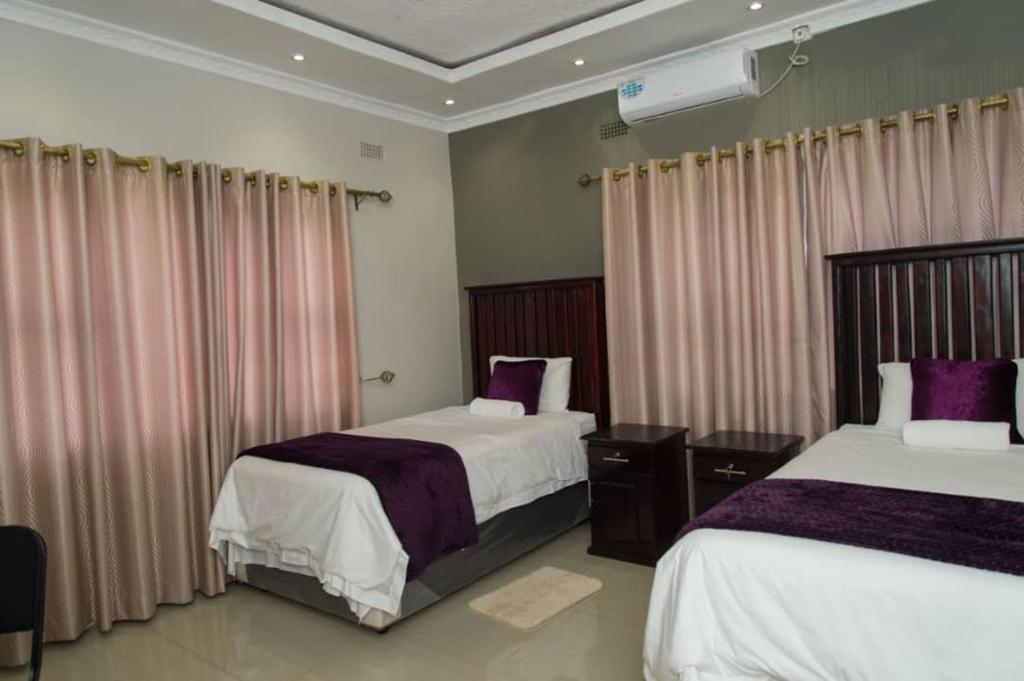 ein Hotelzimmer mit 2 Betten und Vorhängen in der Unterkunft 848 Guest House in Victoriafälle