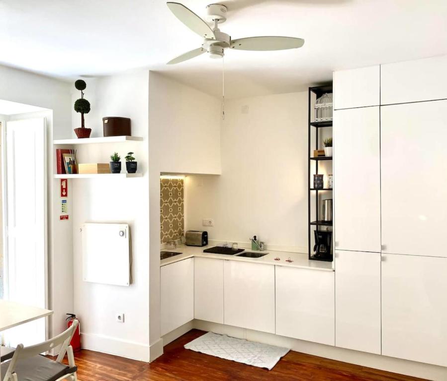 Il comprend une cuisine avec des placards blancs et un ventilateur de plafond. dans l'établissement Modern Studio in the Historic Center of Bica, à Lisbonne