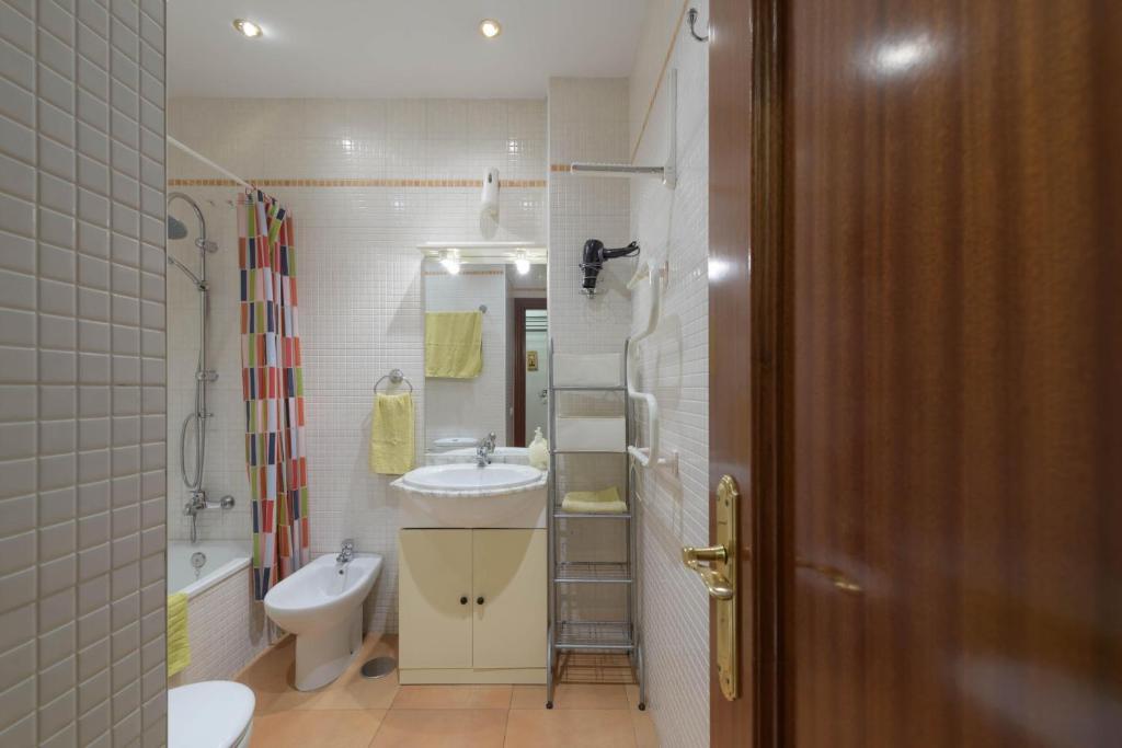 Un baño con lavabo, inodoro y espejo. en Estudio La Colina, en Torremolinos