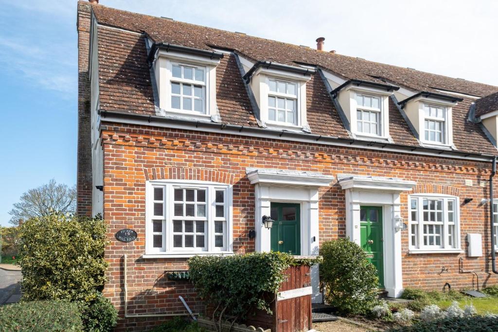 a brick house with white windows and green doors at 15 Mill Field - Aldeburgh Coastal Cottages in Aldeburgh