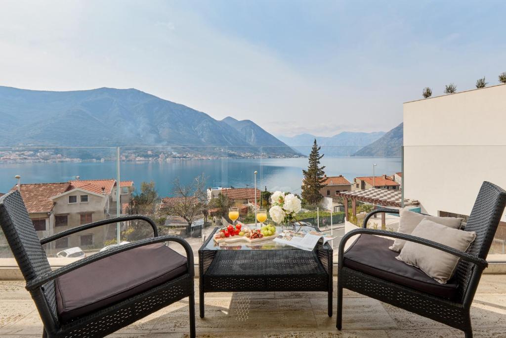 Una mesa y sillas en un balcón con vista al agua. en Neda's Stunning View, en Kotor