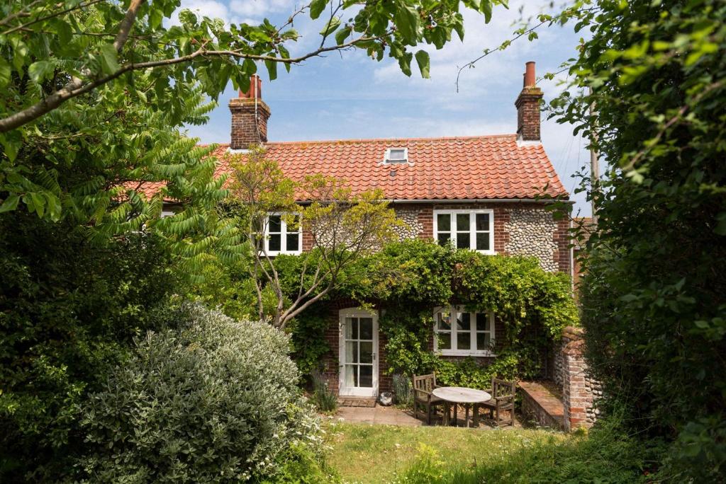 a brick house with a picnic table in front of it at Marlpit Cottage - Norfolk Holiday Properties in Salthouse