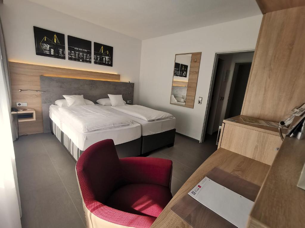 a hotel room with a bed and a chair at Akzent Hotel Körner Hof in Dortmund