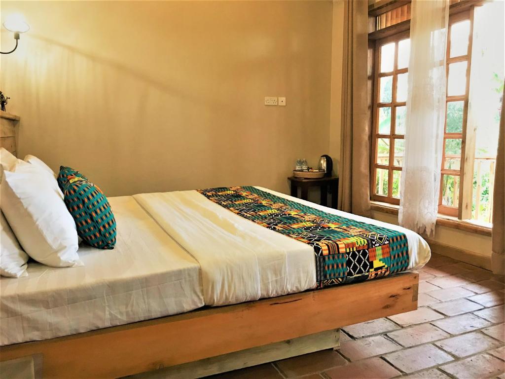 1 cama en un dormitorio con ventana en Kaswa Lodge en Fort Portal