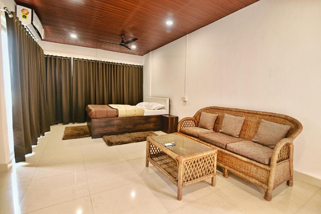 uma sala de estar com um sofá e uma cama em The Upper Homes em Guwahati