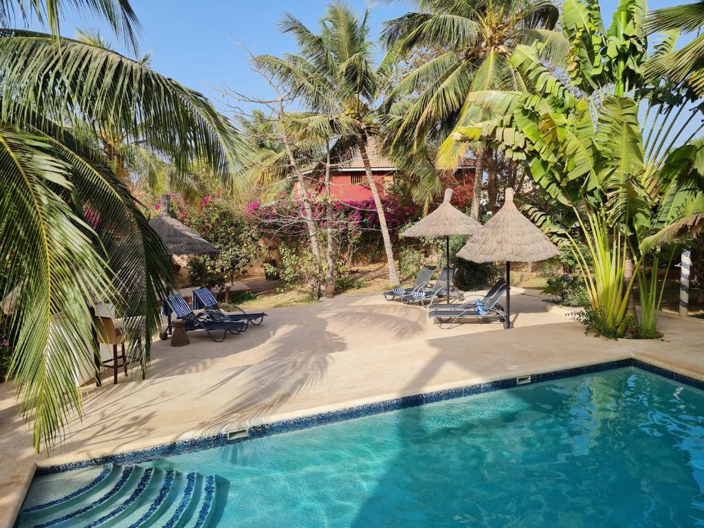 einen Pool mit Stühlen und Sonnenschirmen neben einem Resort in der Unterkunft Le Souimanga Hotel Saly in Saly Portudal