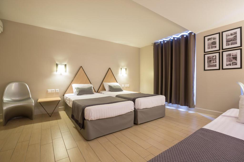 a hotel room with two beds and a chair at Hôtel Amirauté in Toulon