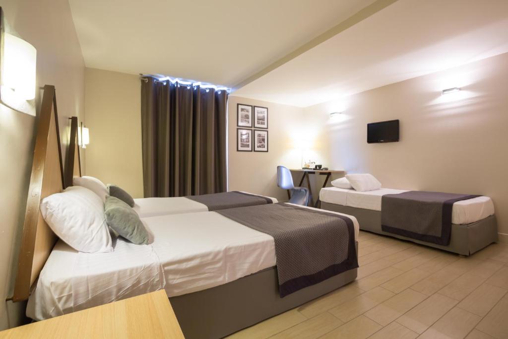 a hotel room with two beds and a desk at Hôtel Amirauté in Toulon