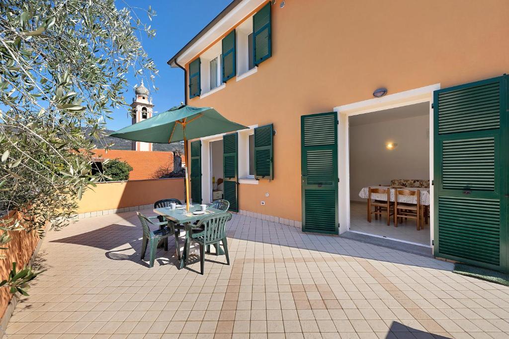 Un patio con una mesa y sillas y una sombrilla. en Appartamento Ferla La Taggiasca, en Stellanello