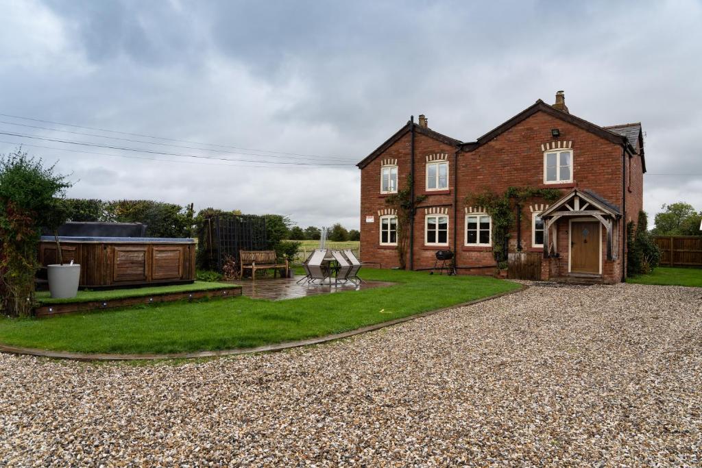 a large brick house with a gravel driveway at Welsh Cottage with Hot Tub - Jubilee House in Wrexham