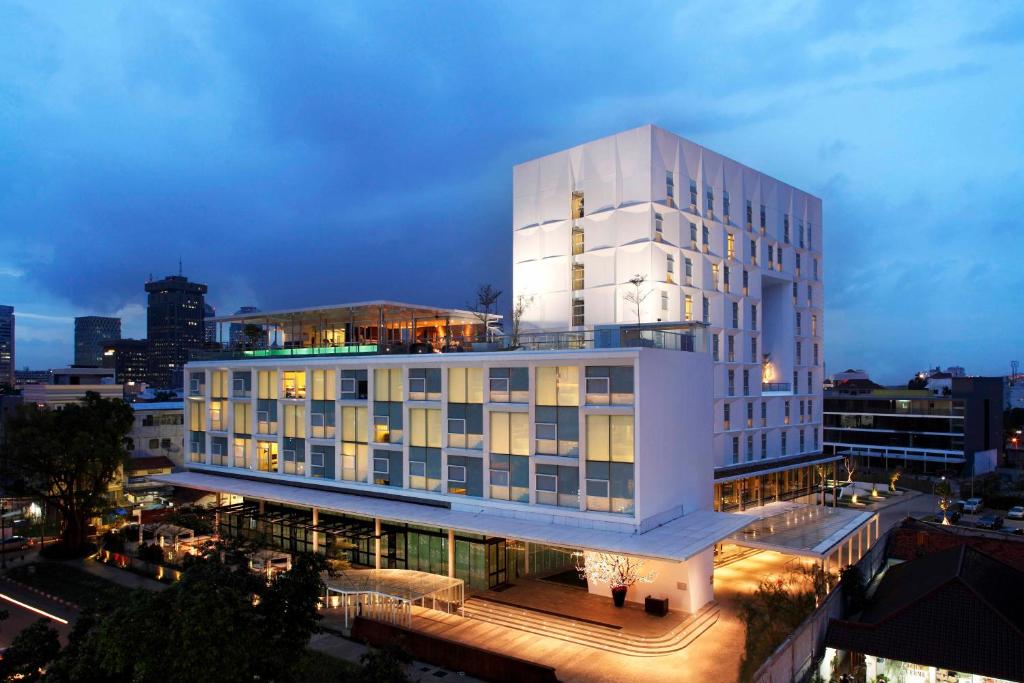 a large white building with a lit up facade at Morrissey Hotel in Jakarta