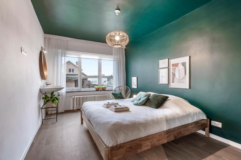 1 dormitorio con 1 cama grande y pared verde en Ruim, rustgevend glv app met warme kleuraccenten en Middelkerke