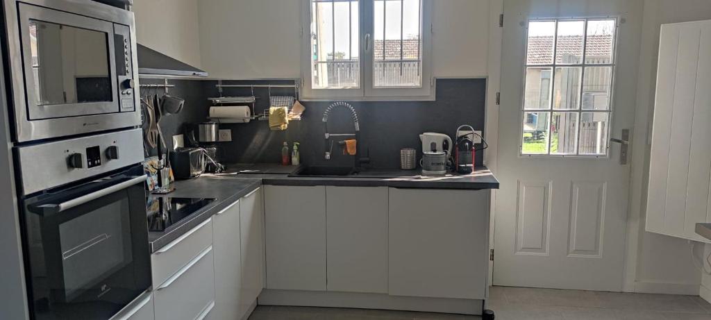 a kitchen with white cabinets and a stove top oven at Agréable Maison, toute équipée, proche du lac d'Arjuzanx in Morcenx