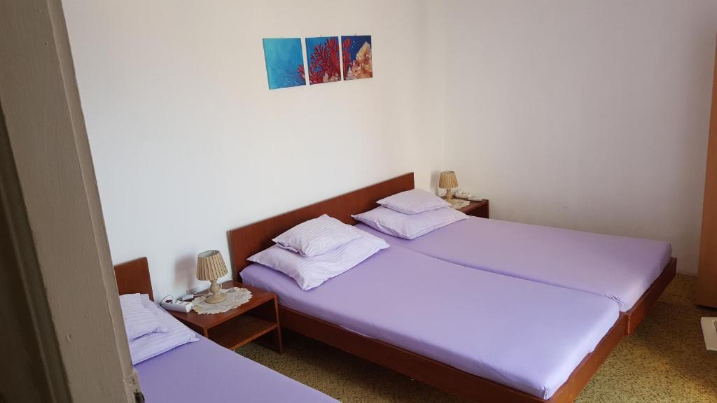 2 Betten in einem kleinen Zimmer mit violetter Bettwäsche in der Unterkunft Rooms Milena in Lopud Island