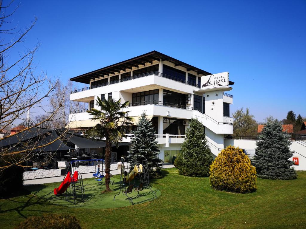 a white building with trees in front of it at Hotel Le Pont in Prijedor