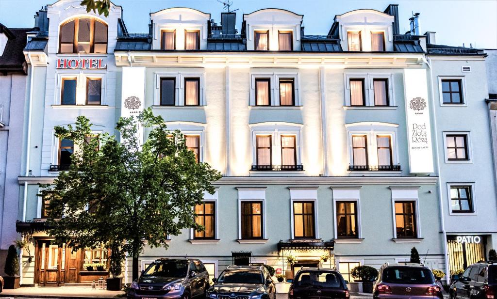 a large white building with cars parked in front of it at Hotel Pod Złotą Różą in Kielce