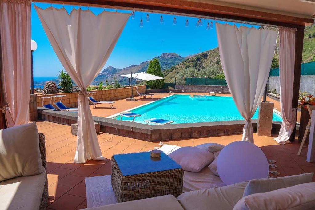 een woonkamer met een zwembad en een bank bij Poolhaus Sicilysun Holidays Giulia in Letojanni