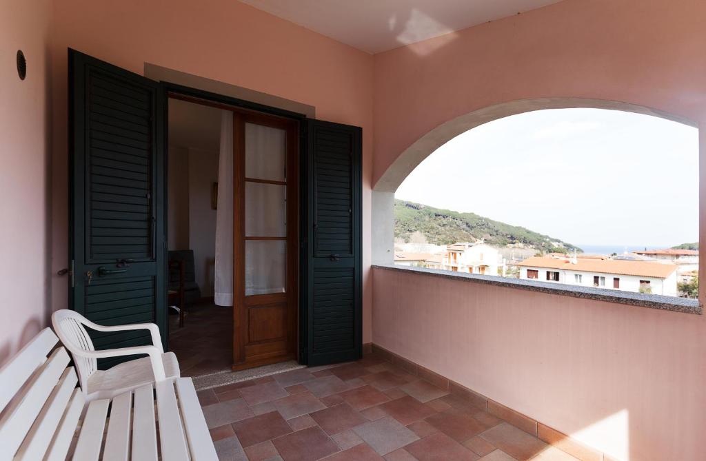 a porch with a white bench and an open door at Casa Fiori di Pesco - Goelba in Marciana Marina