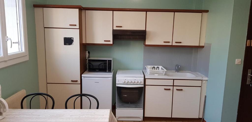 La cuisine est équipée de placards blancs, d'une cuisinière et d'un évier. dans l'établissement Appartement T1bis de 30m2, à Dijon