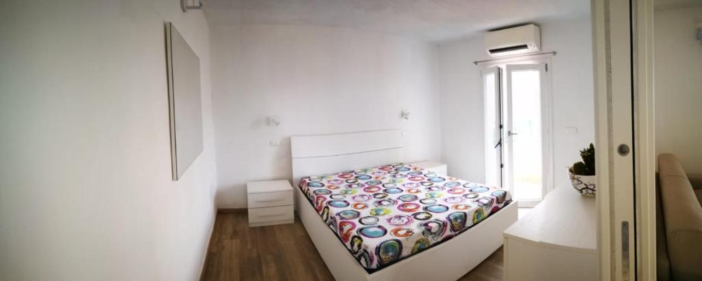 um pequeno quarto com uma cama num quarto branco em La casa dei fichi em Porto Azzurro
