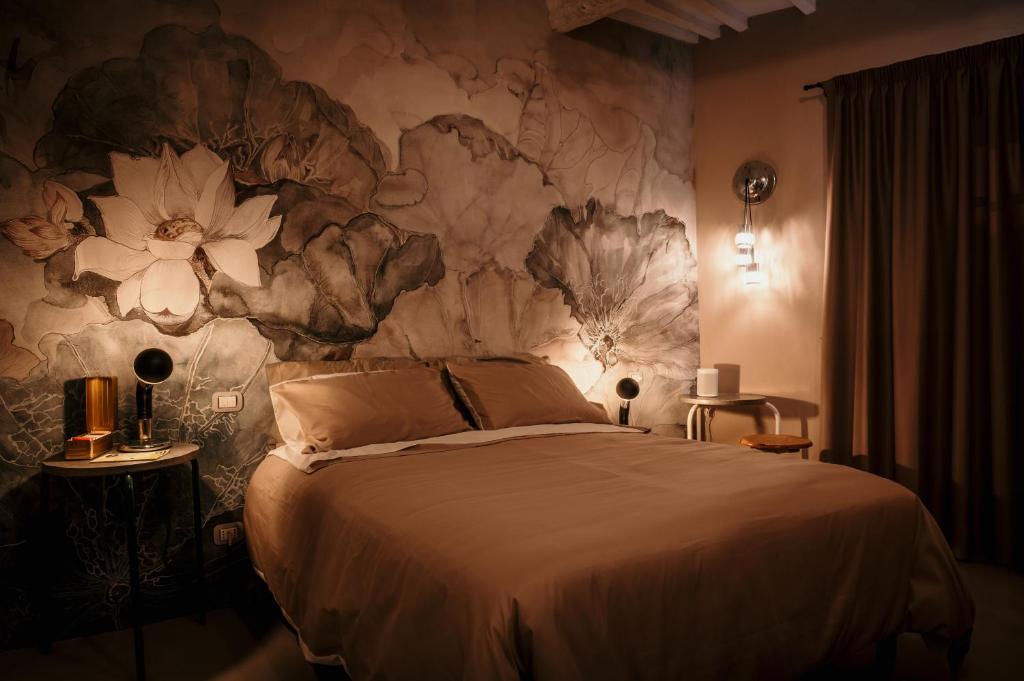 1 dormitorio con 1 cama grande y pared de flores en B&B La Castellina en Abbadia San Salvatore