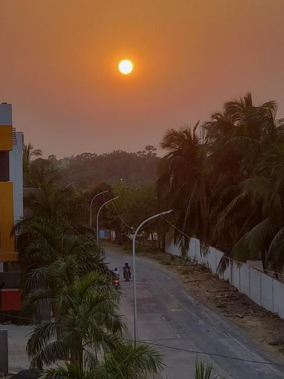 a sunset over a street with palm trees and a street light at Casa De Diu in Diu