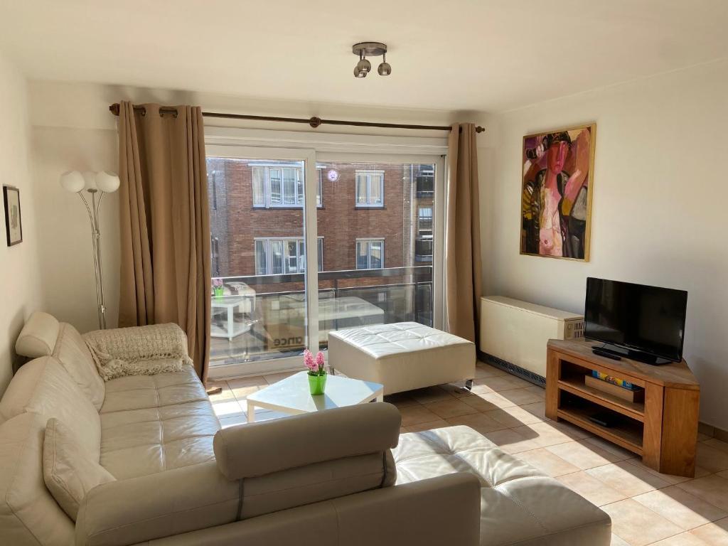 uma sala de estar com um sofá e uma televisão em Ruim zonnig appartement op 50m van strand em Ostend