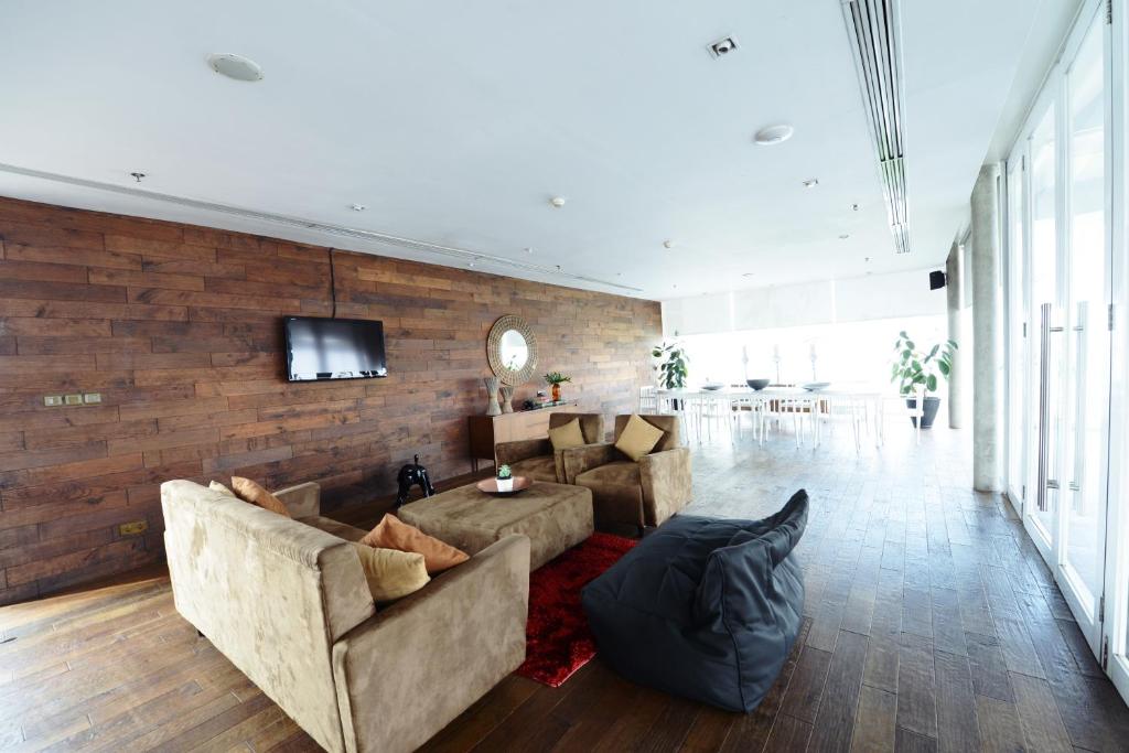 a living room with a couch and a tv on a brick wall at Morrissey Hotel in Jakarta