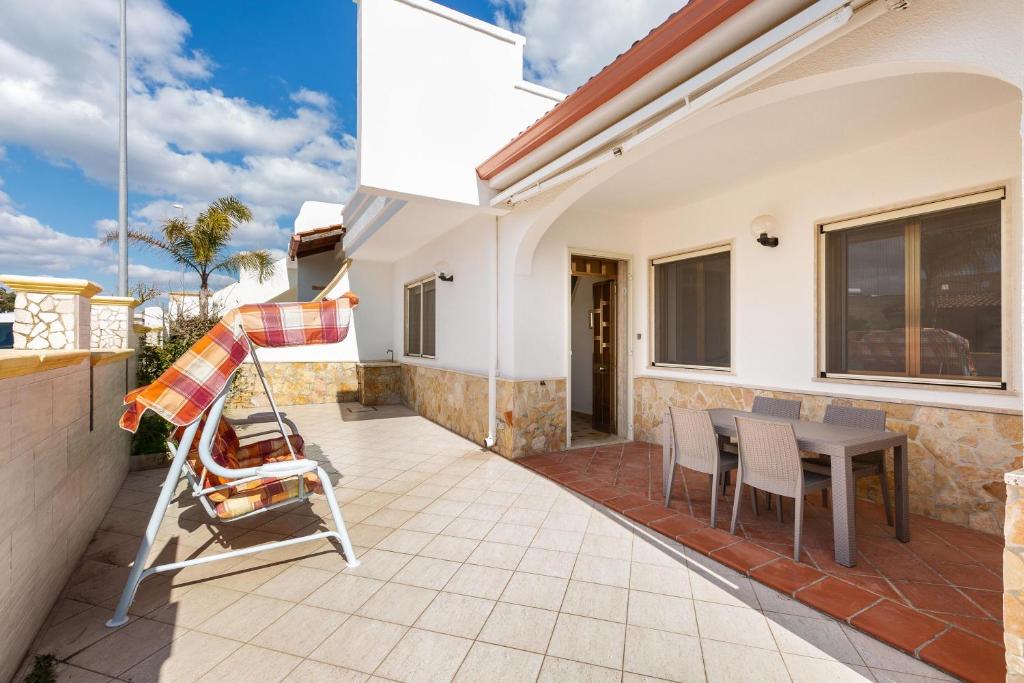a patio with a table and chairs on a house at Villa Rosa di Mare by BararHouse in Torre Lapillo