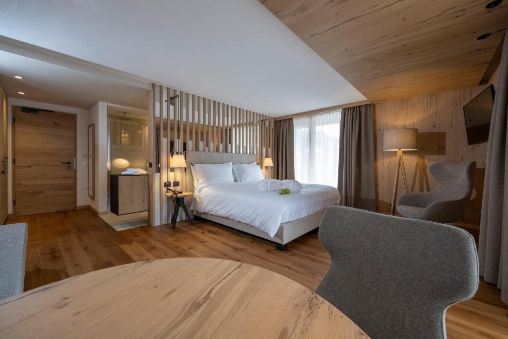 a bedroom with a bed and a table and chairs at Ciampedie Luxury Alpine Spa Hotel in Vigo di Fassa