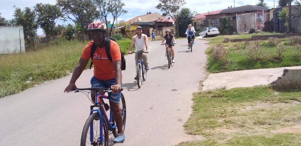 a group of people riding bikes down a road at Authentic Bicycle Tours and Backpackers in Soweto