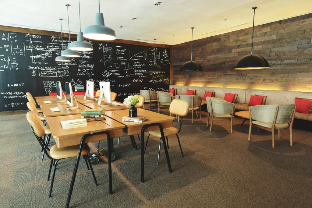 a dining room with a table and chairs and a chalkboard at Morrissey Hotel in Jakarta
